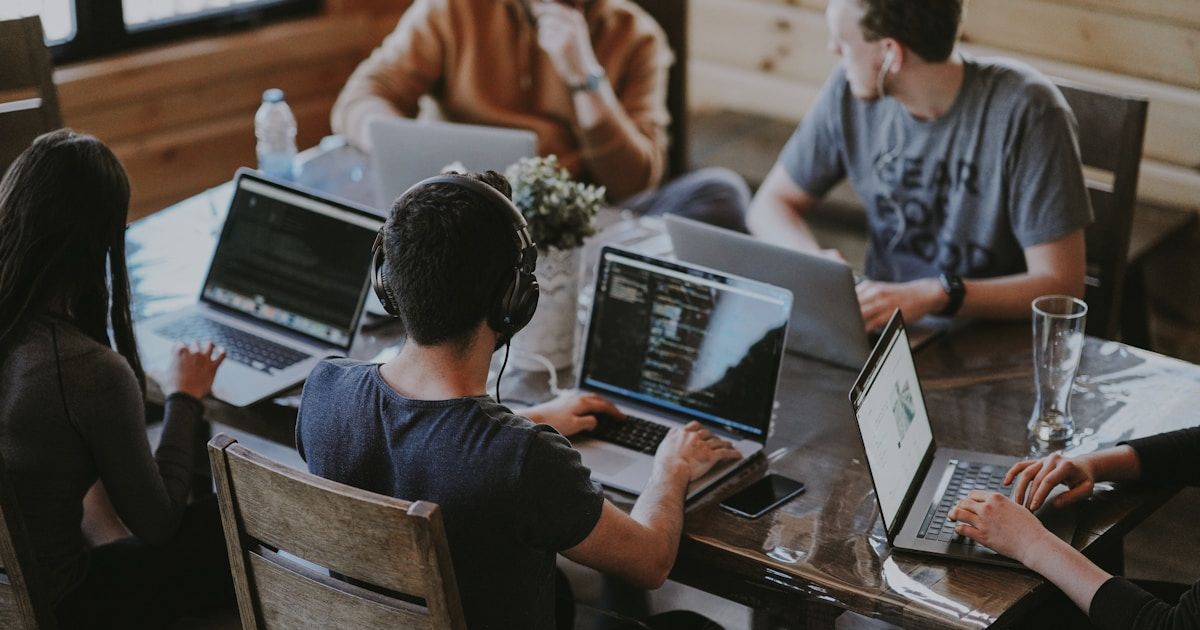 Équipe professionnelle souriante collaborant devant un ordinateur portable affichant un logiciel web dans un bureau moderne